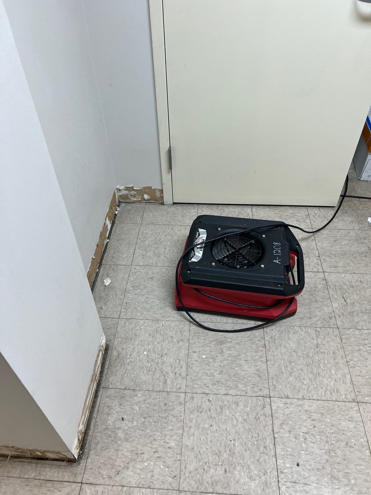 An air mover drying water-damaged walls