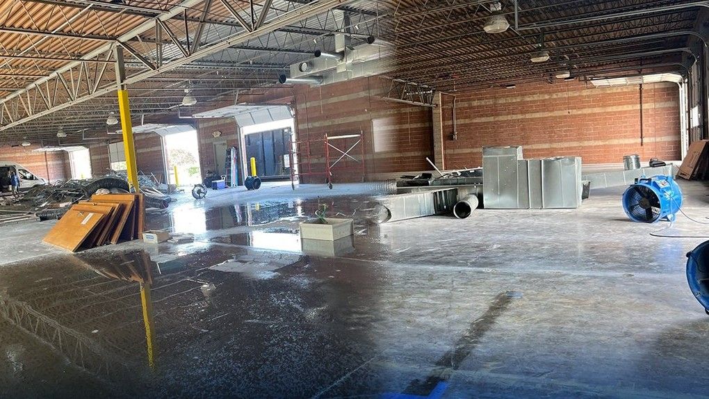 Drying fans on the wet floor of a storm-damaged warehouse