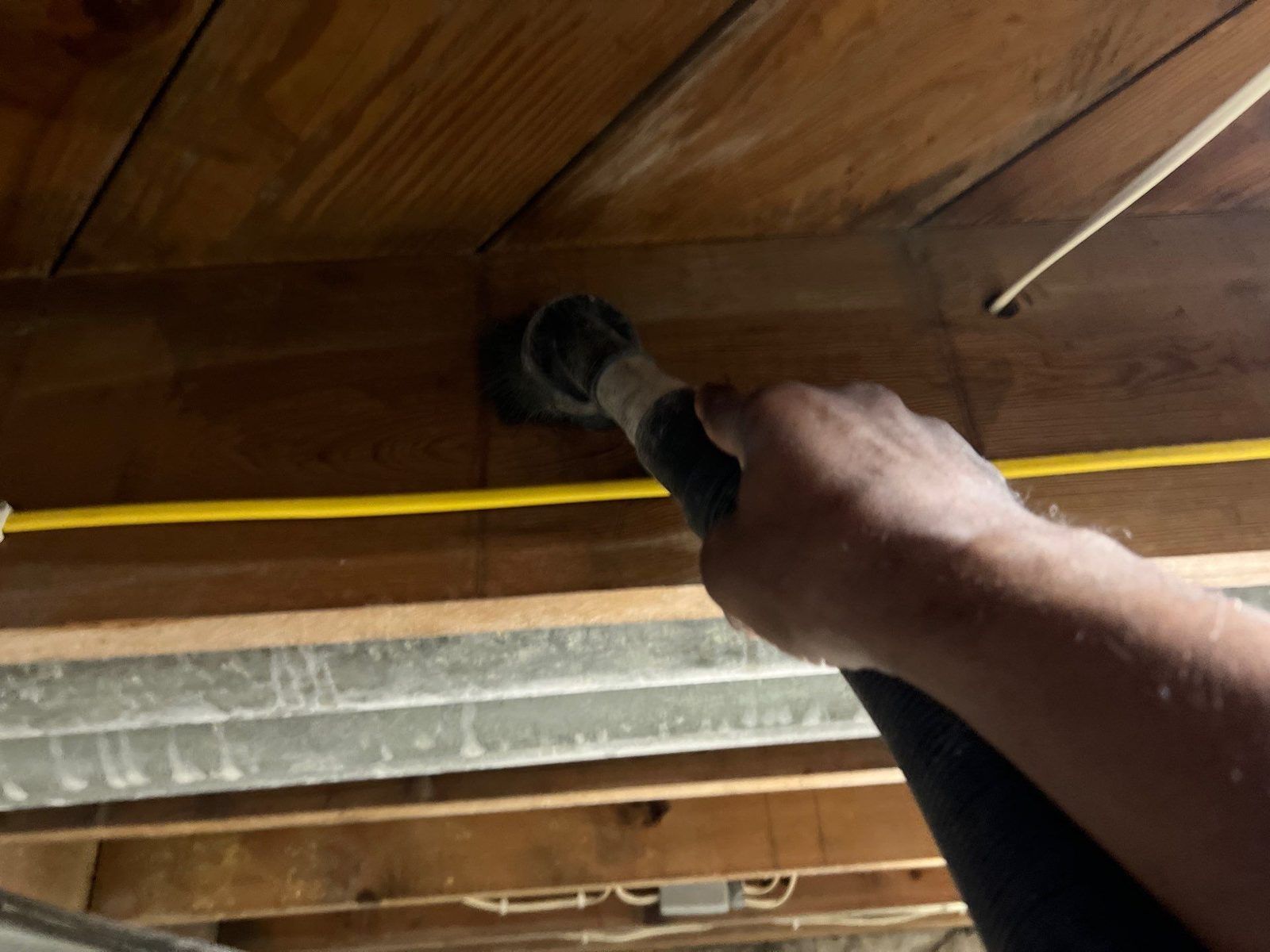 HEPA vacuuming basement ceiling joists during mold remediation