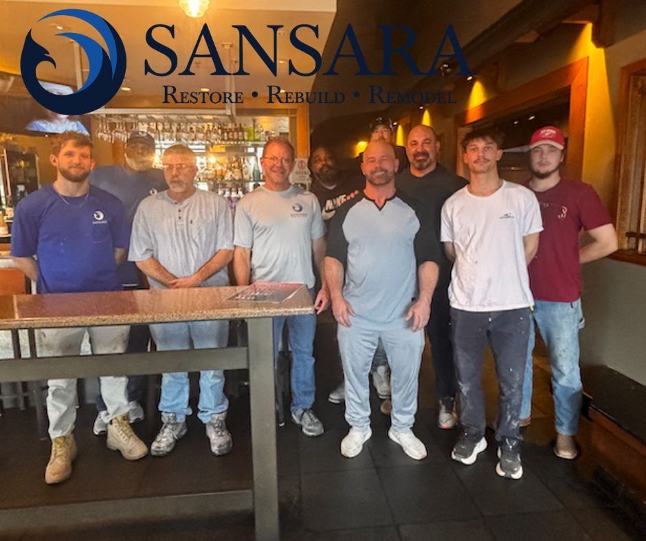 The Sansara team in front of the Sansara logo