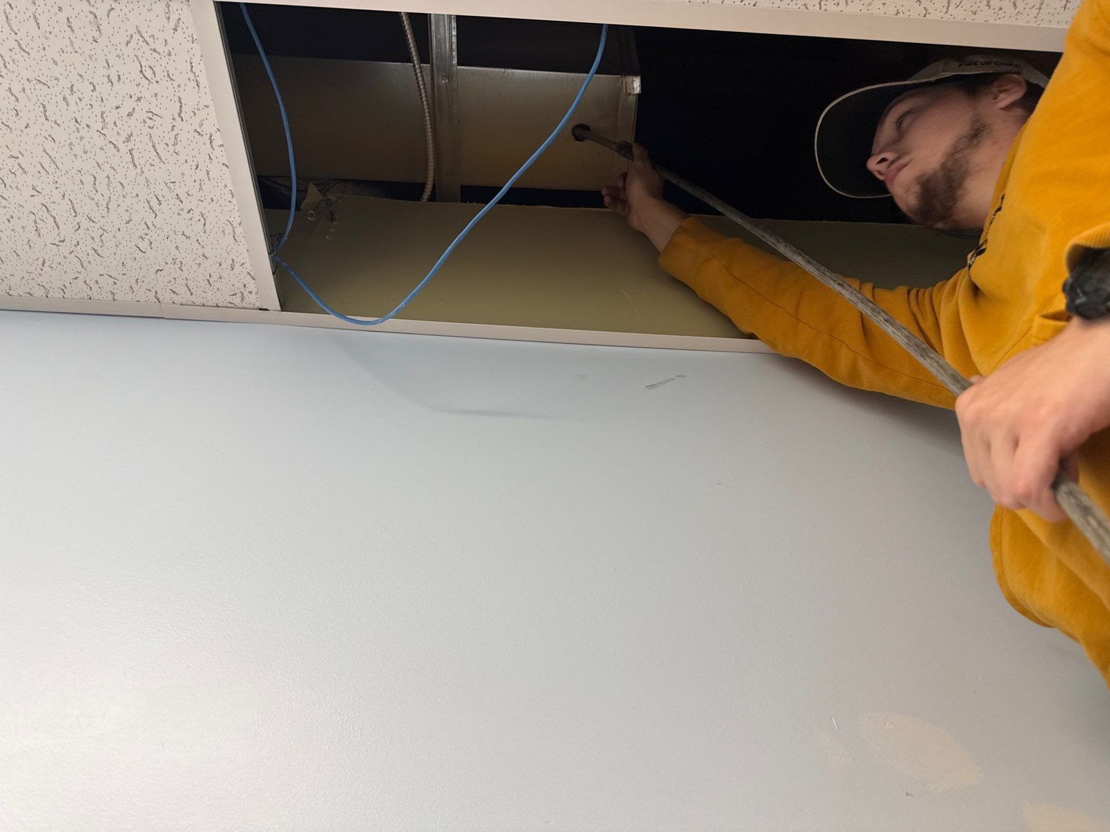 A Sansara technician working above a commercial drop ceiling